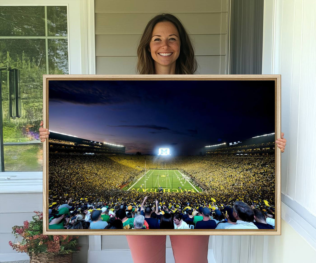 The wall art features a glowing M in this Michigan Wolverines Football Team Ann Arbor Stadium Canvas Print.