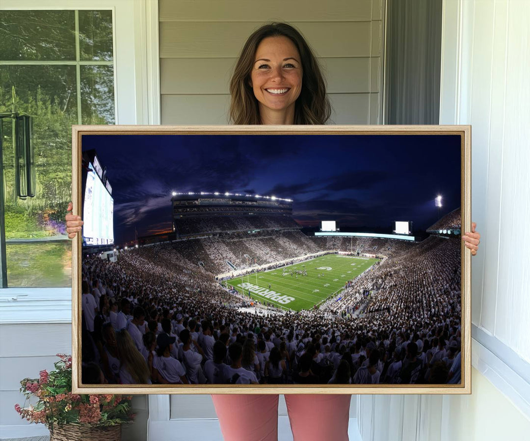 A packed football stadium at night, with bright lights and fans in white, depicted in a Michigan State Spartans Stadium wall art.