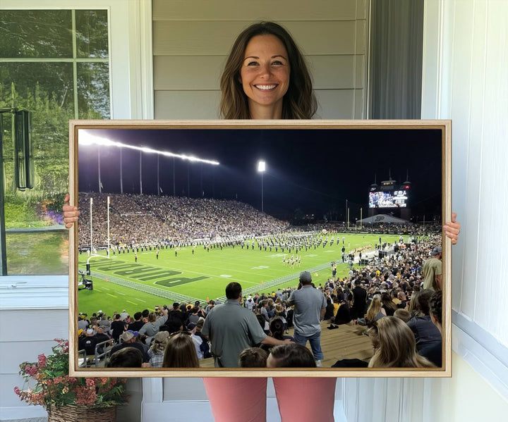 A painting depicting the Purdue Boilermakers football game at Ross-Ade Stadium is illuminated under gallery-quality lights.