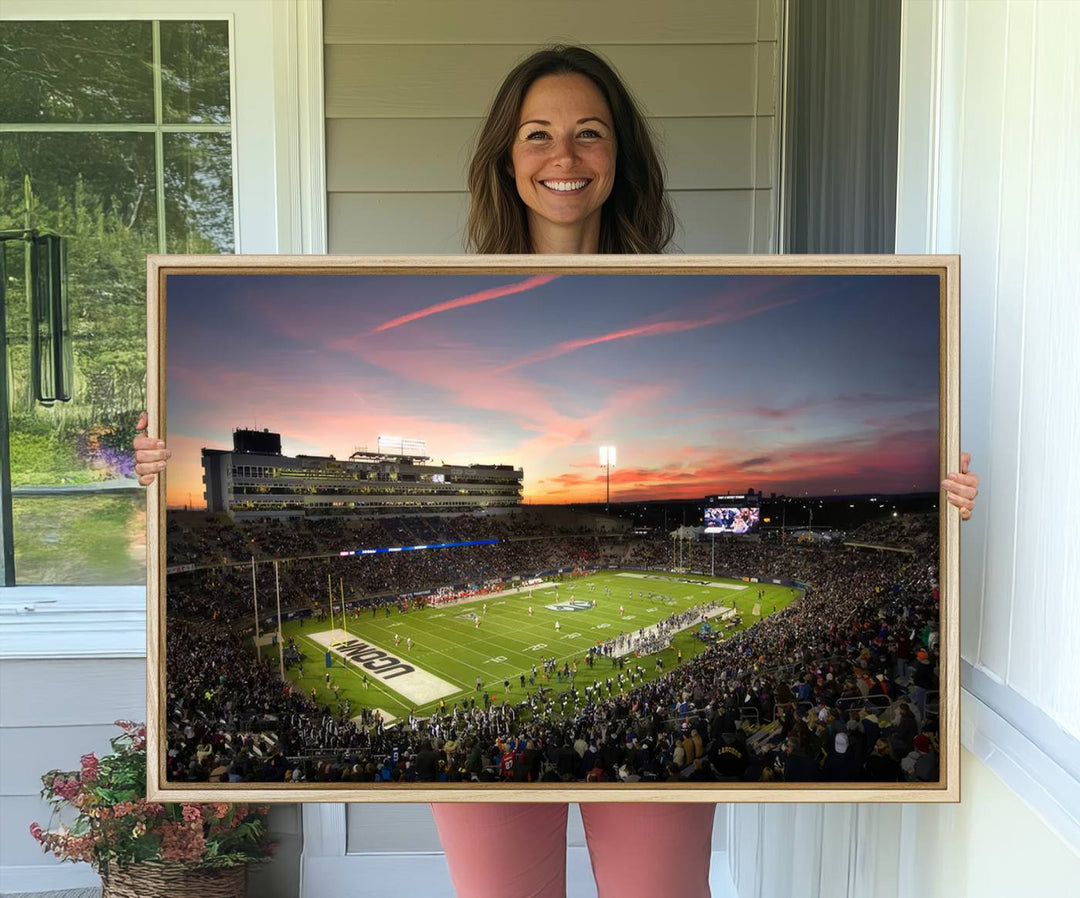 This wall art canvas print captures UCONN Huskies fans energizing a sunset scene at East Hartfords Pratt & Whitney Stadium.