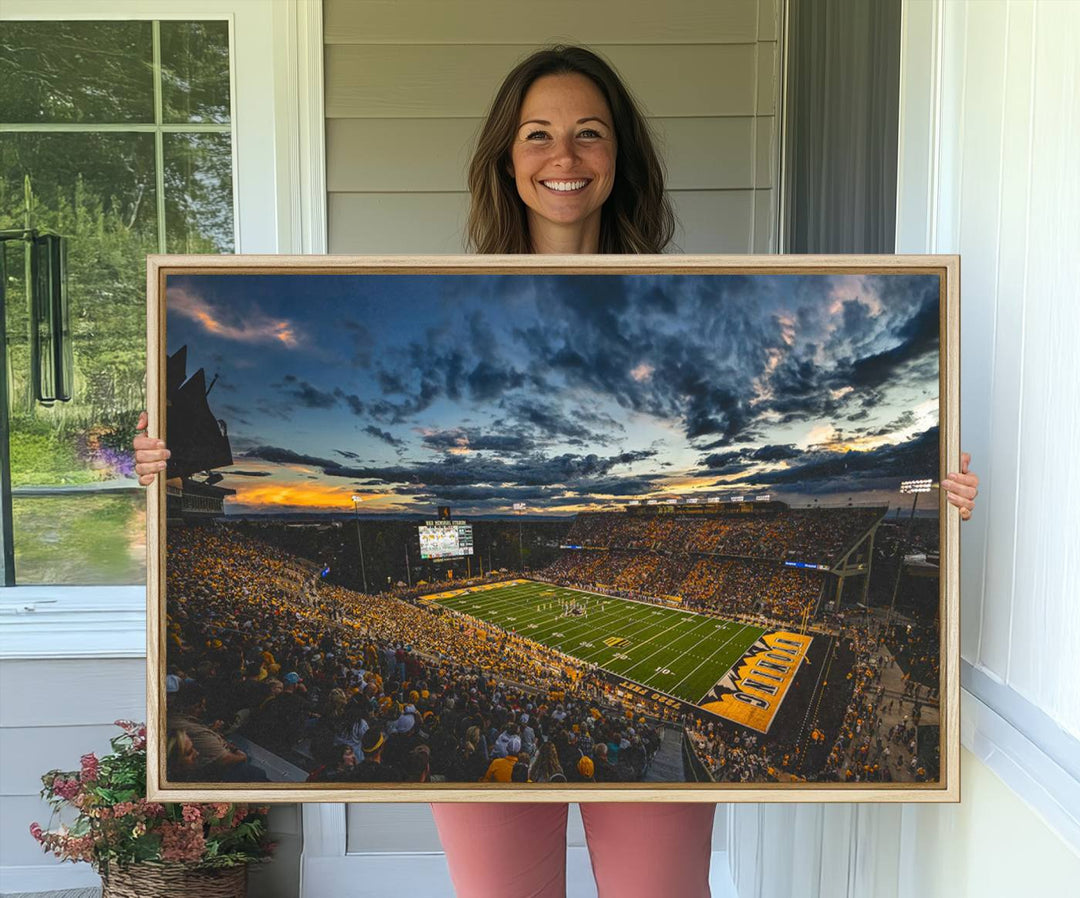 Laramies War Memorial Stadium Print captures a stunning scene of the stadium during sunset, set under a partly cloudy sky illuminated by bright lights.