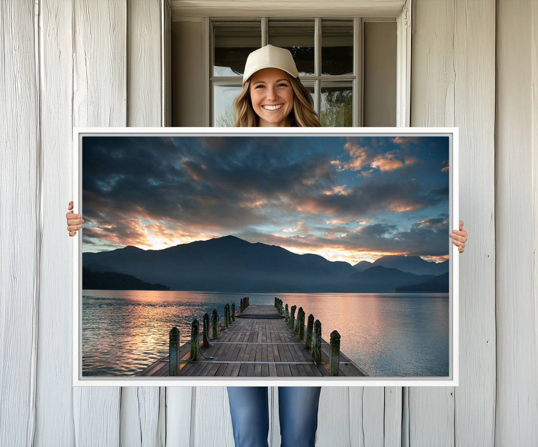 The Mountain Lake Wood Pier Canvas Wall Art depicts a serene lake and mountains, enhancing the beauty of any space.