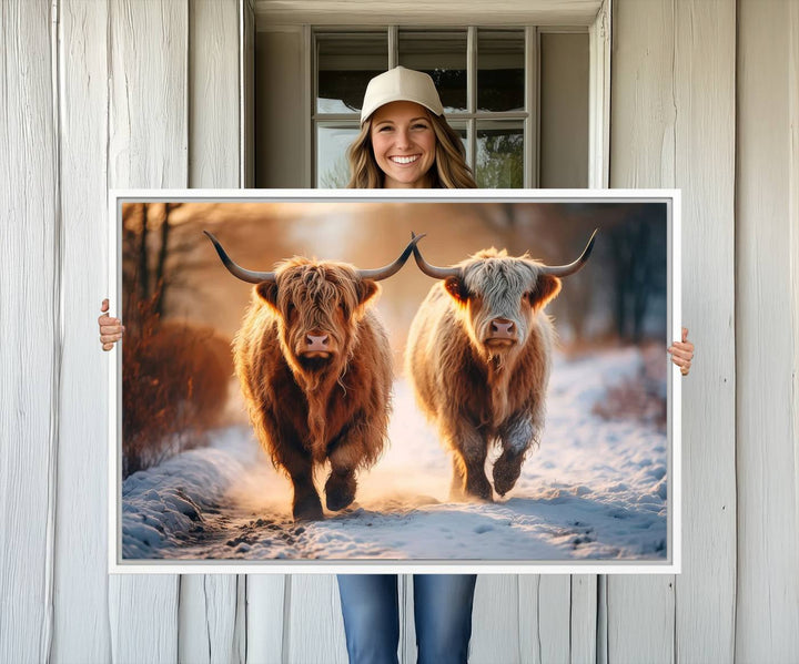 The wall art is a Scottish Highland Cow Horn canvas print featuring cows on a snowy path bathed in warm sunlight, serving as a rustic decor piece.