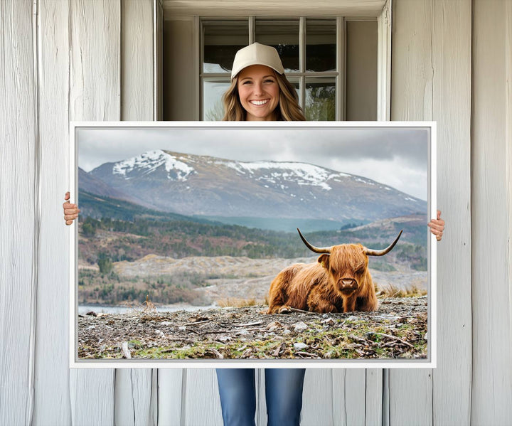 Highland Cow Horn Farm Wall Art Canvas Print is displayed against a wooden wall featuring a mountainous backdrop.