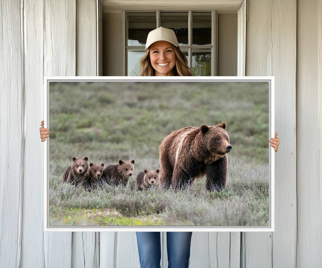 The large canvas print titled "Queen of the Tetons, 399 Grizzly Bear Cubs" showcases majestic wildlife photography of a bear and her cubs walking through the grass. This stunning canvas wall art, handmade in the USA, adds a charming touch to any room with its rustic decor appeal.