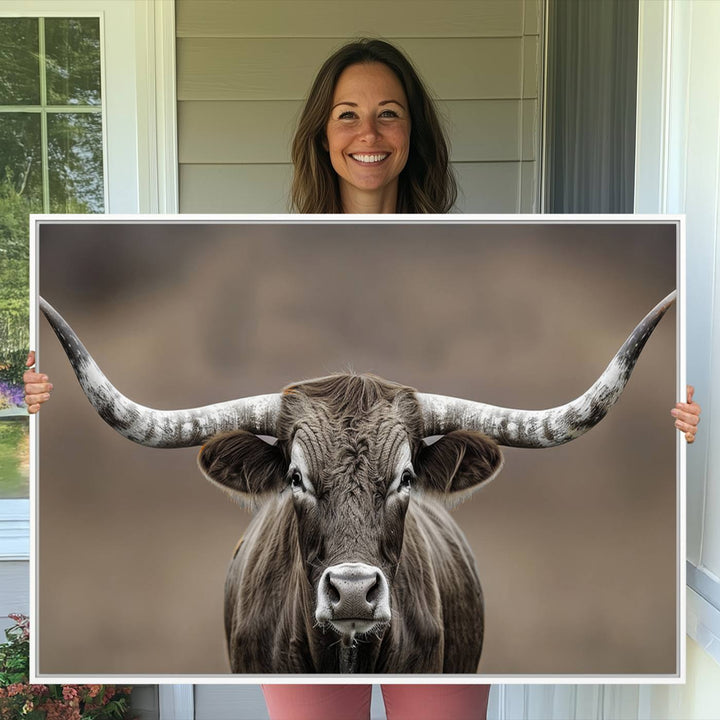 A close-up of a longhorn bull facing forward is featured in the Framed Texas Test-1, set against a blurred brown background.