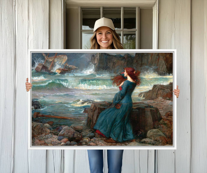 The Miranda by the Shore Wall Art Canvas Print depicts a woman in a blue dress standing by the sea, watching a shipwreck.