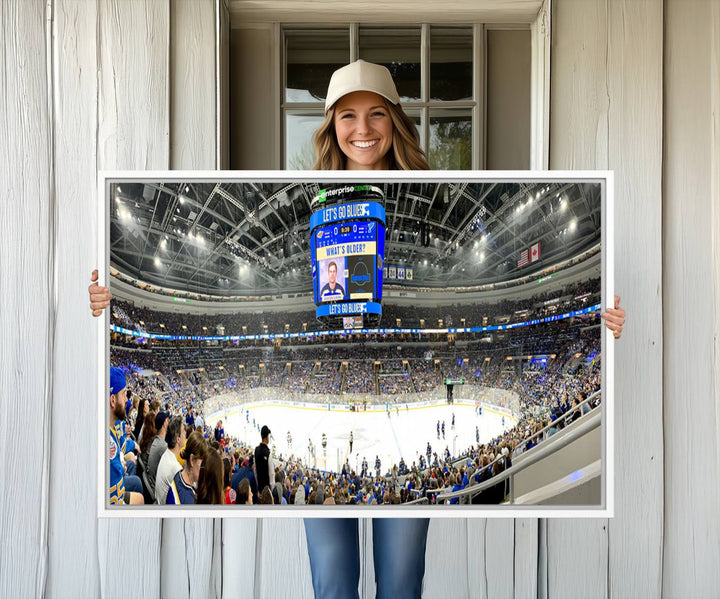 Wall art prints depicting the bustling scenes of the St. Louis Blues being cheered on by a full house at the Enterprise Center, beneath a large scoreboard.