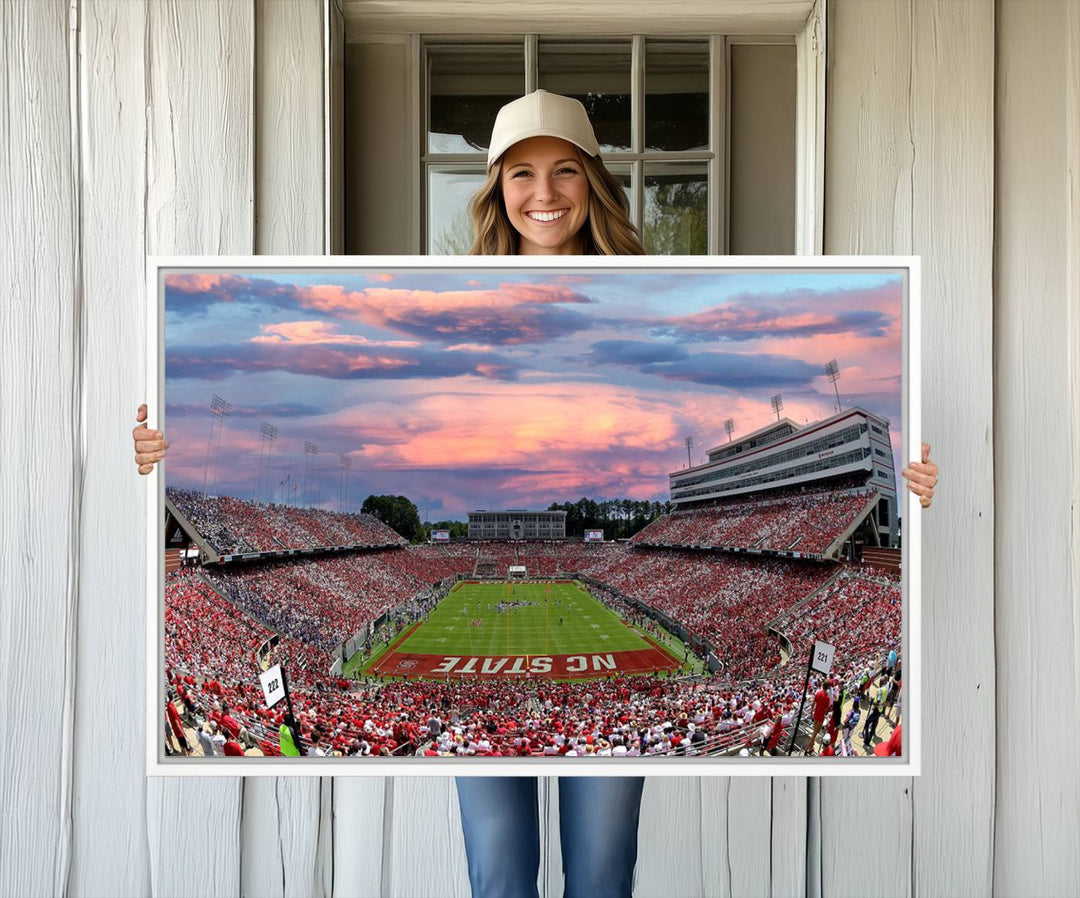 The wall art captures an NC State Wolfpack game under a vibrant sunset on triple canvas.