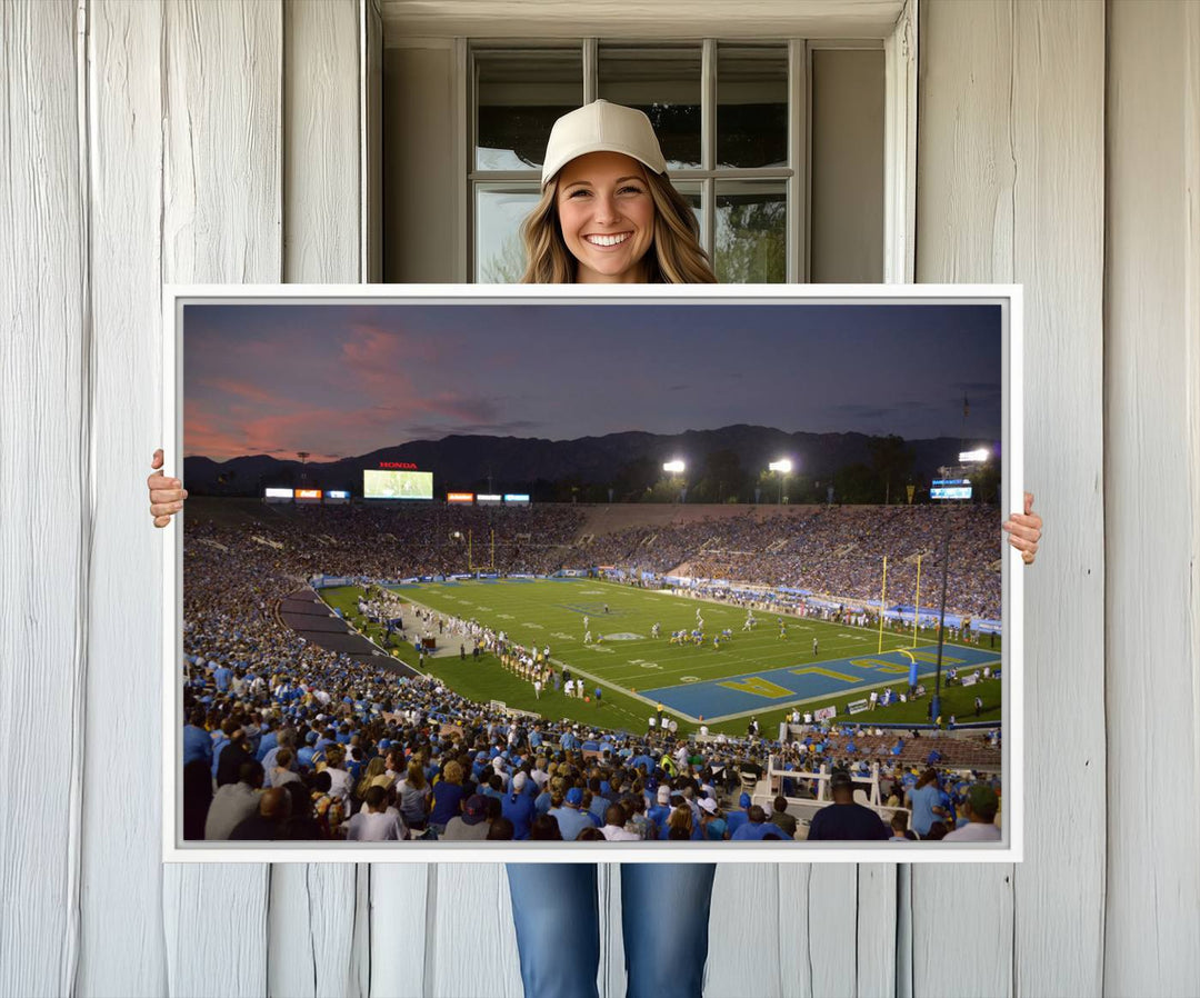 Admire the stunning wall art canvas depicting a UCLA Bruins game with a sunset over the Pasadena Rose Bowl Stadium.