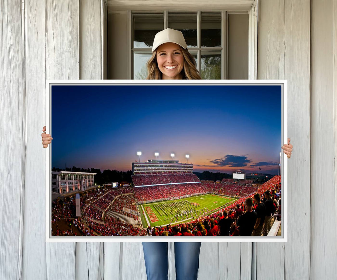 The Wolfpack Football Team Print captures a band and crowd at dusk in a premium canvas art style at Raleigh Carter-Finley Stadium.