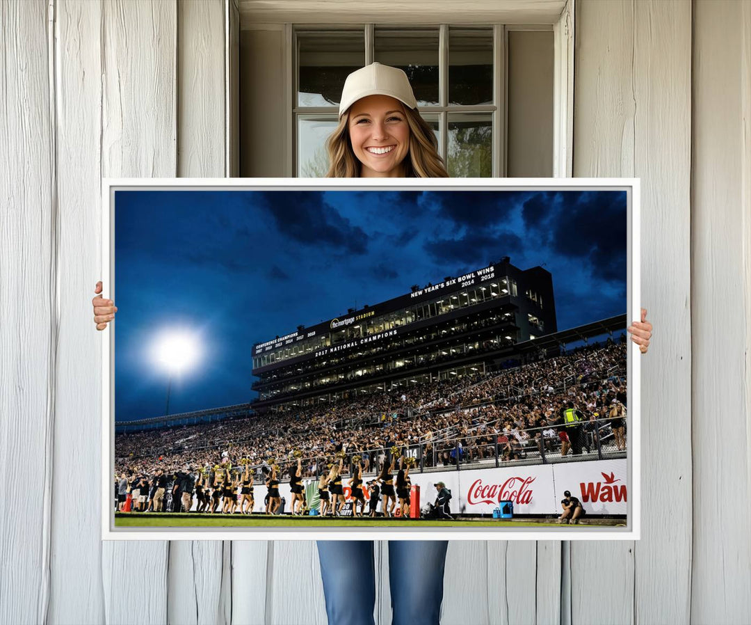 A gallery-quality canvas print depicting a stadium packed with fans under a night sky, highlighting the UCF Knights Football Team.