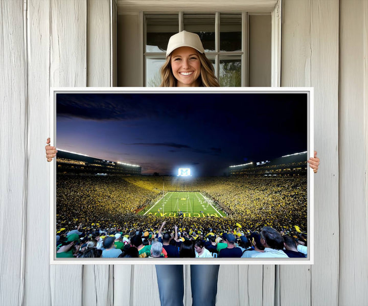 The wall art features a glowing M in this Michigan Wolverines Football Team Ann Arbor Stadium Canvas Print.