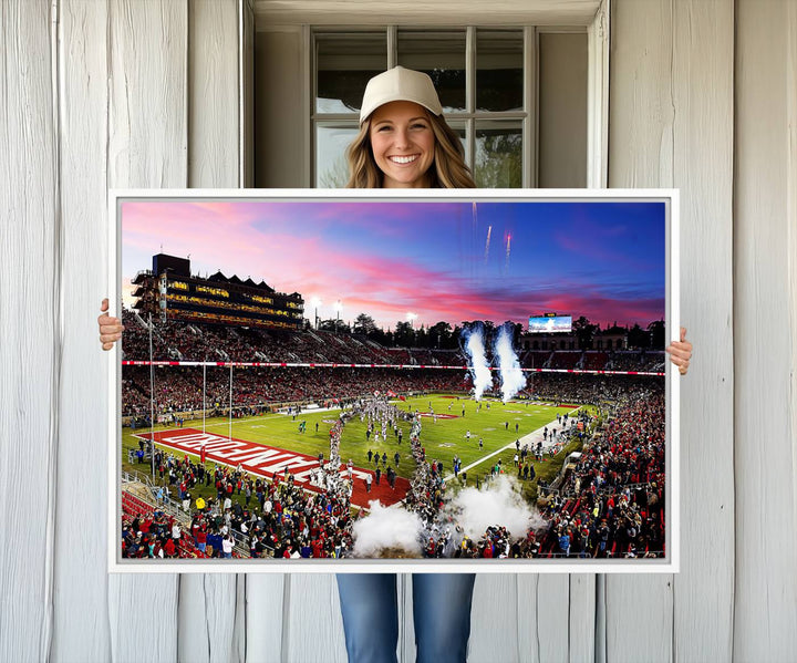 The wall art features a canvas print of the Stanford Cardinal football team, capturing players, fireworks, and smoke against the backdrop of a sunset at Stanford Stadium.