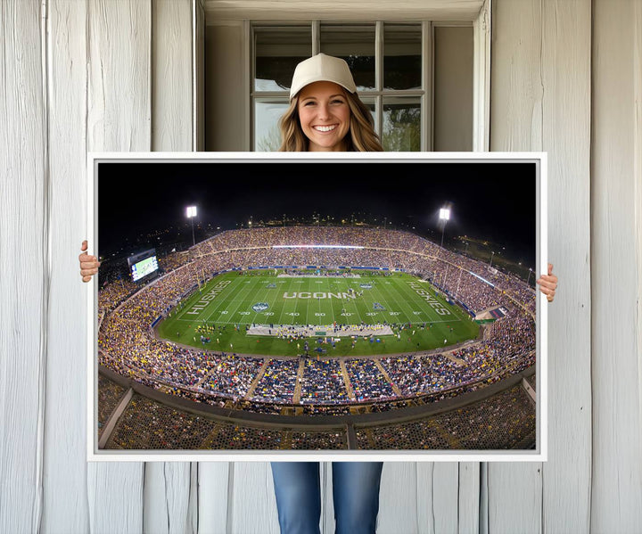 A large football stadium at night, featuring the UCONN Huskies, is depicted on the East Hartford Pratt & Whitney Stadium Wall Art Canvas Print.