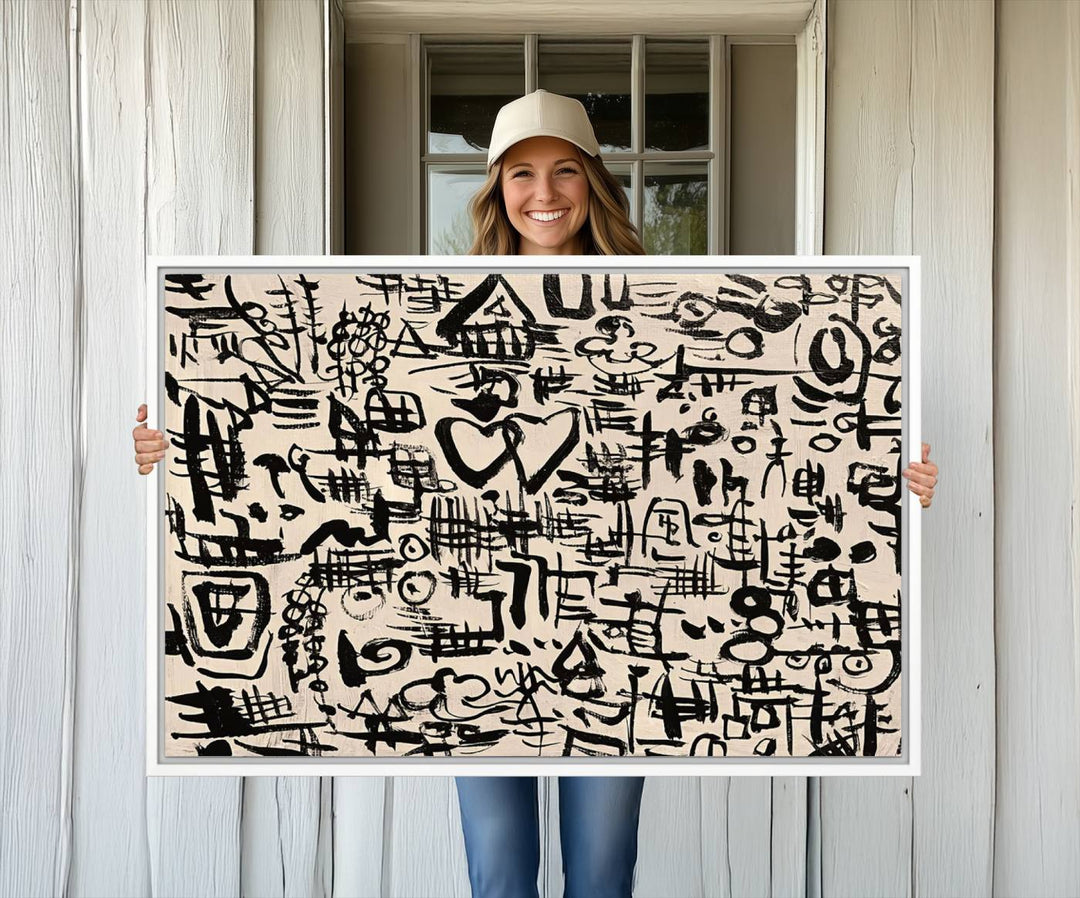 The Abstract Love and Chaos canvas is a museum-quality print featuring black symbols on a beige background, adorned with a heart and scribble design. It is framed to enhance its artistic appeal.