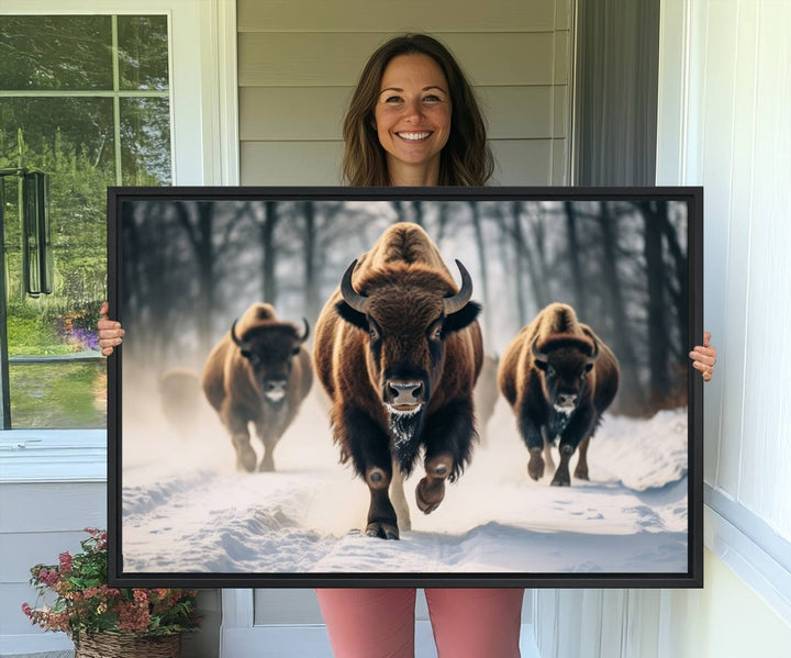 Wall art titled Cow Bighorn shows three bison running through snow in a forest.