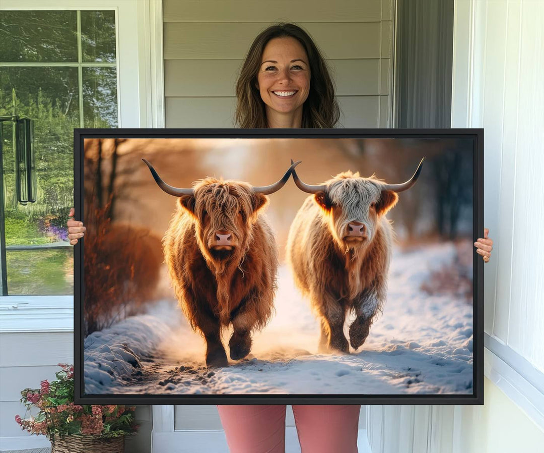 The wall art is a Scottish Highland Cow Horn canvas print featuring cows on a snowy path bathed in warm sunlight, serving as a rustic decor piece.