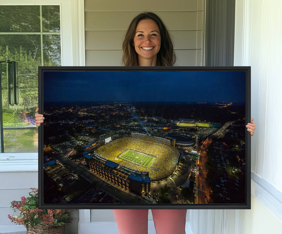 Aerial view of Michigan Stadium at night, surrounded by city lights, depicted on a Michigan Wolverines wall art canvas print.