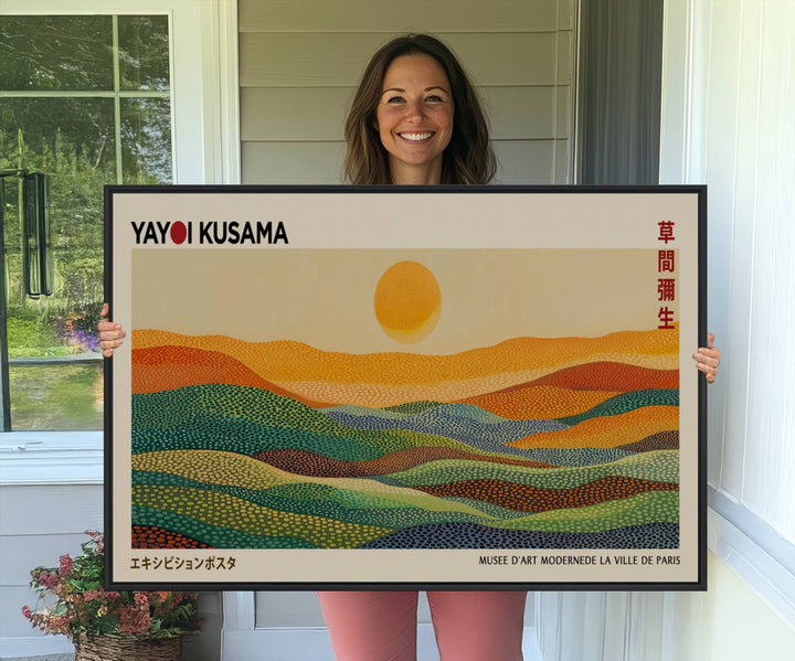 A framed Yayoi Kusama 1986 wall art print showcases a vibrant abstract landscape with colorful, wavy dots and a sun above the horizon.