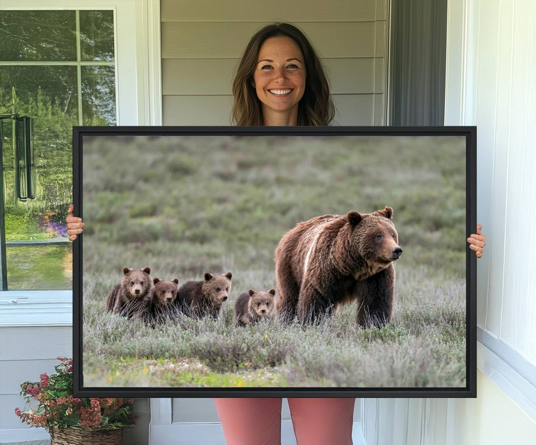 The large canvas print titled "Queen of the Tetons, 399 Grizzly Bear Cubs" showcases majestic wildlife photography of a bear and her cubs walking through the grass. This stunning canvas wall art, handmade in the USA, adds a charming touch to any room with its rustic decor appeal.