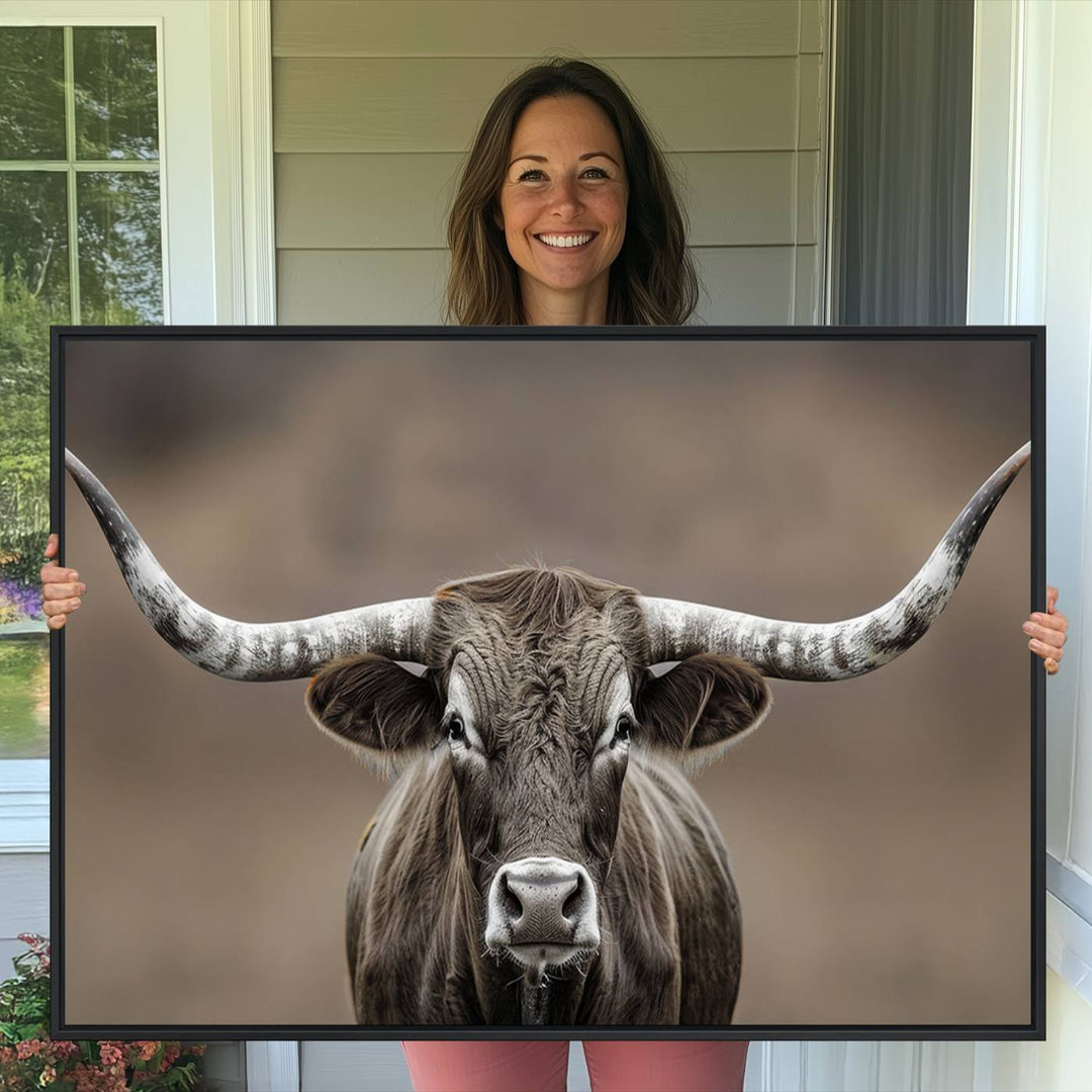 A close-up of a longhorn bull facing forward is featured in the Framed Texas Test-1, set against a blurred brown background.