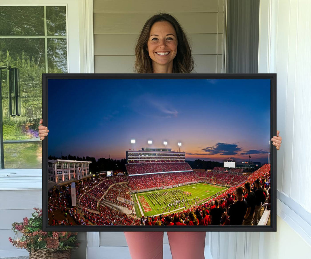 A vibrant and dynamic painting captures the essence of an electrifying night game at Carter-Finley Stadium, highlighting the illuminated atmosphere as the NC State Wolfpack competes under bright stadium lights.