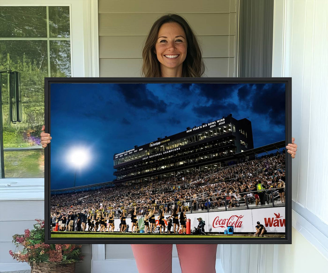 A gallery-quality canvas print depicting a stadium packed with fans under a night sky, highlighting the UCF Knights Football Team.