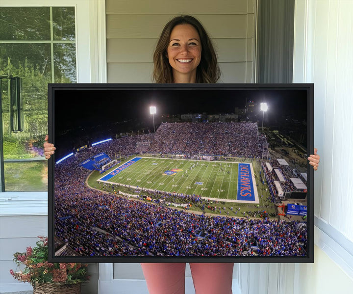 A canvas depicting an aerial view of the University of Kansas Memorial Stadium, showcasing bright lights and a lush green field at night.