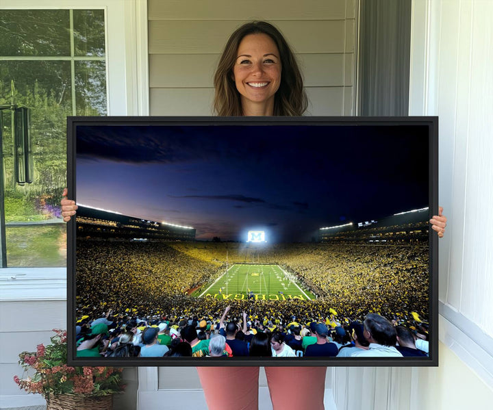 The wall art features a glowing M in this Michigan Wolverines Football Team Ann Arbor Stadium Canvas Print.