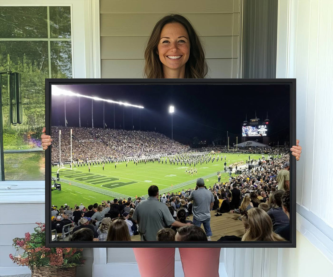 A painting depicting the Purdue Boilermakers football game at Ross-Ade Stadium is illuminated under gallery-quality lights.