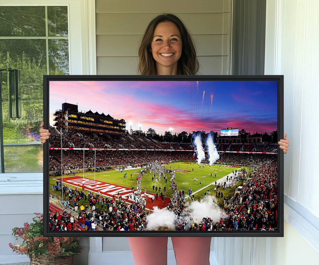 The wall art features a canvas print of the Stanford Cardinal football team, capturing players, fireworks, and smoke against the backdrop of a sunset at Stanford Stadium.