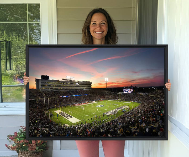 This wall art canvas print captures UCONN Huskies fans energizing a sunset scene at East Hartfords Pratt & Whitney Stadium.