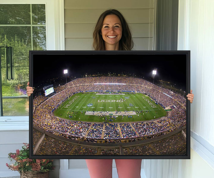 A large football stadium at night, featuring the UCONN Huskies, is depicted on the East Hartford Pratt & Whitney Stadium Wall Art Canvas Print.