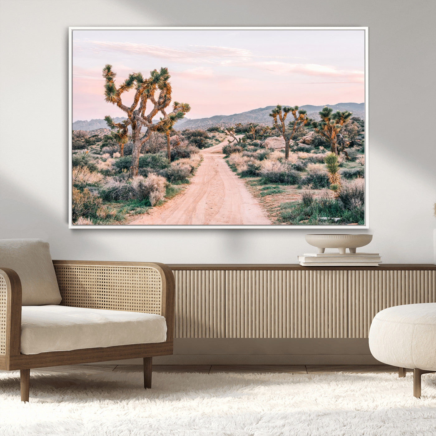 A dusty road winding through Joshua Tree National Park, framed by iconic twisted trees and warm desert tones under a soft pastel sky.