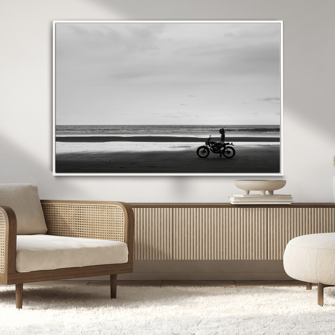 A motorcyclist on a vast beach, gazing at the ocean, capturing a moody and tranquil coastal adventure in black and white.