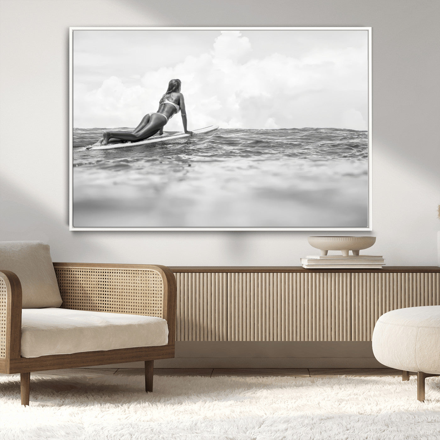 A black and white ocean scene featuring a surfer girl waiting on her board, gazing at the horizon, capturing a tranquil and adventurous coastal moment.