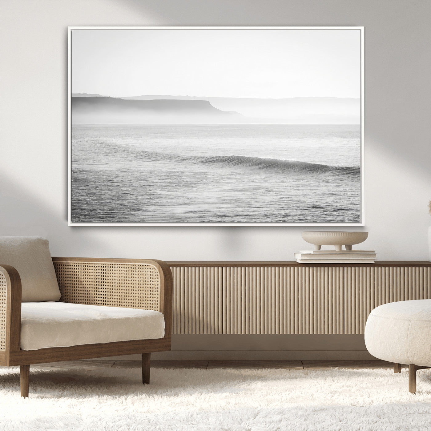 A black and white minimalist seascape featuring soft rolling waves and misty distant cliffs, creating a serene and timeless coastal atmosphere.