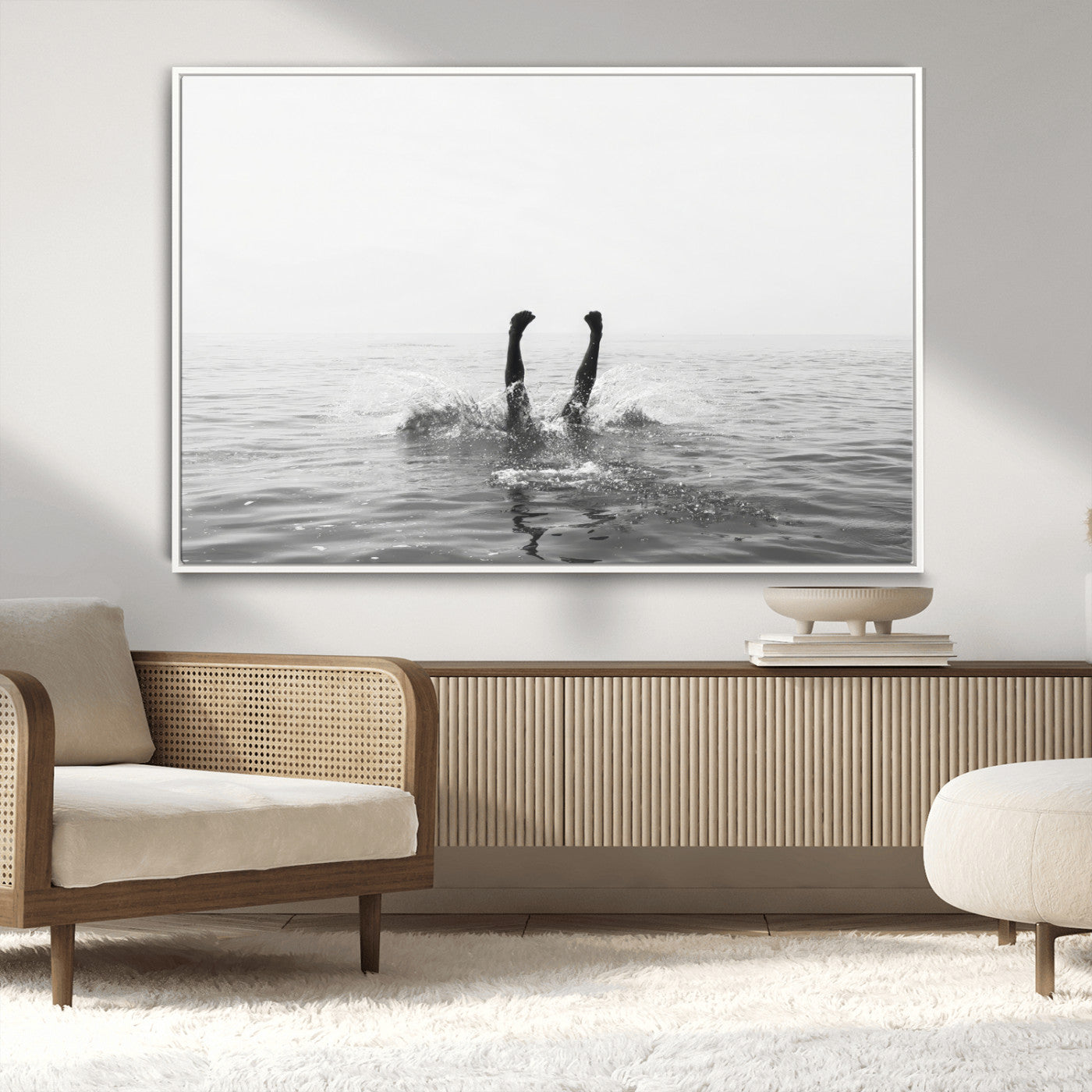 A black and white minimalist water scene capturing a playful splash as a swimmer dives upside down, creating a carefree and artistic aquatic aesthetic.