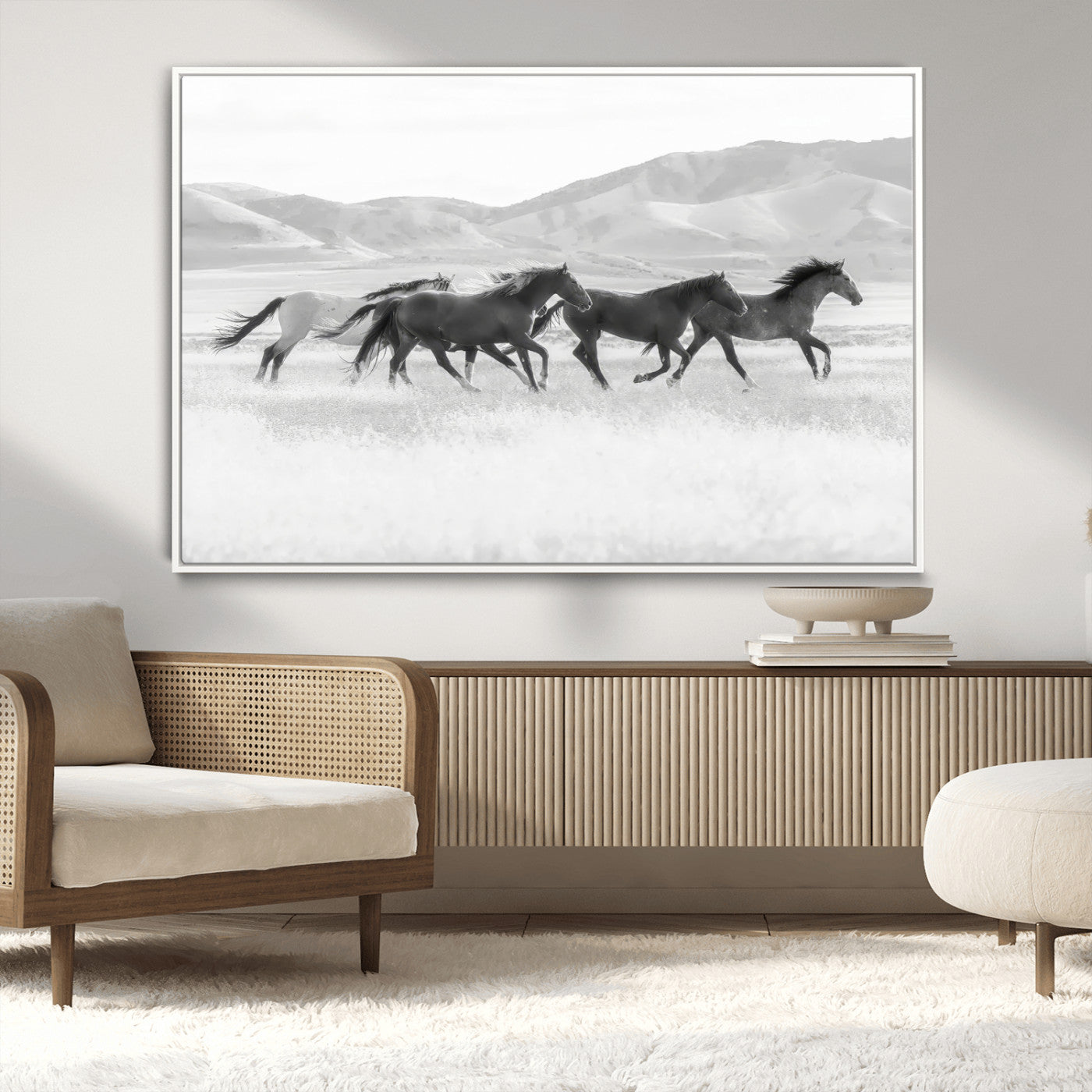 A black and white image of wild horses running freely across an open grassland, capturing the power and beauty of untamed nature in a rustic western setting.