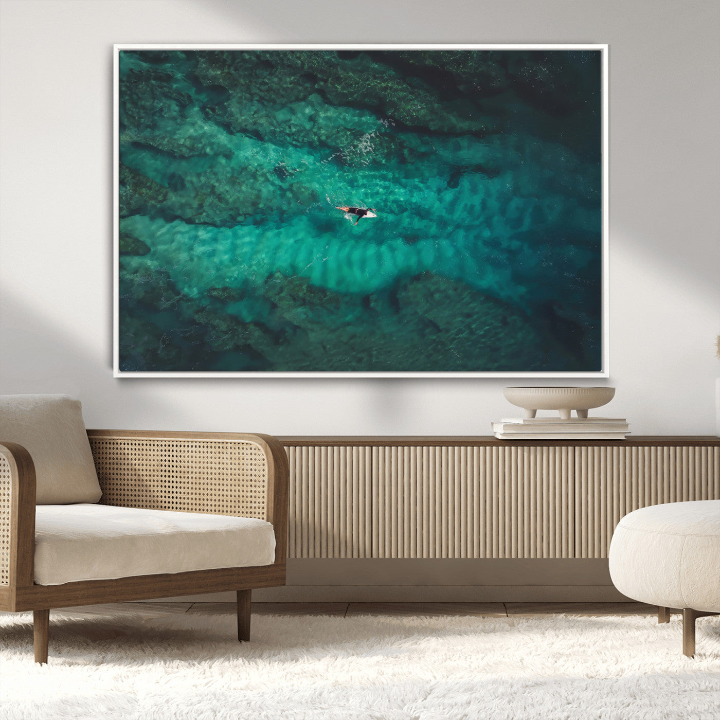 An aerial view of a solo surfer paddling through crystal-clear turquoise waters over a sunlit reef, capturing the beauty and serenity of open water surfing.