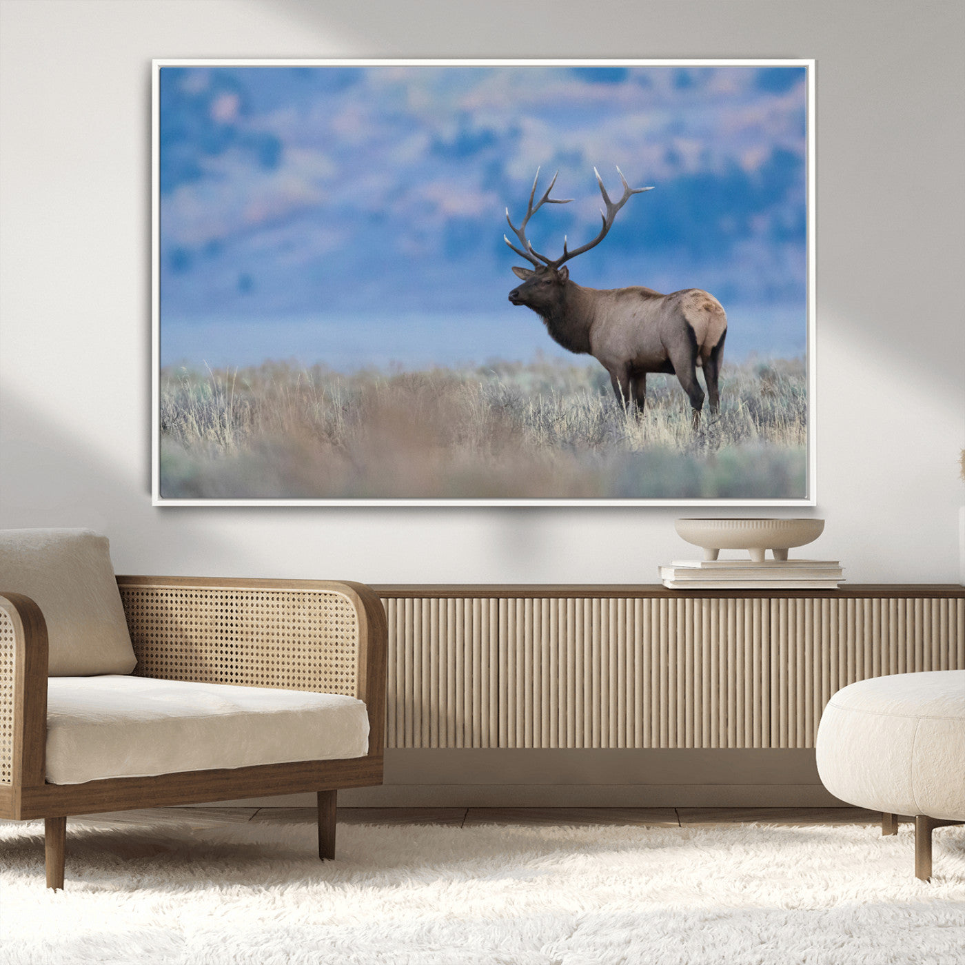 Elk with large antlers standing in open field, mountains blurred in background, perfect for rustic cabin or lodge-style decor.