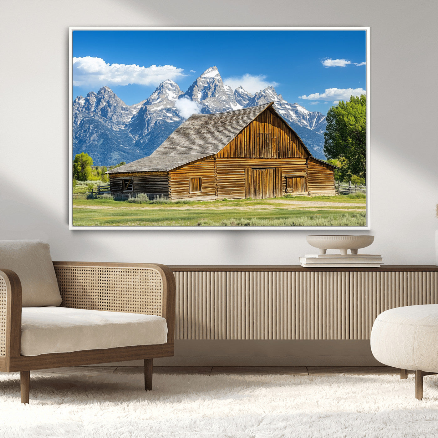 A rustic wooden barn sits in front of towering mountain peaks under a clear blue sky, perfect for farmhouse or cabin style interiors.