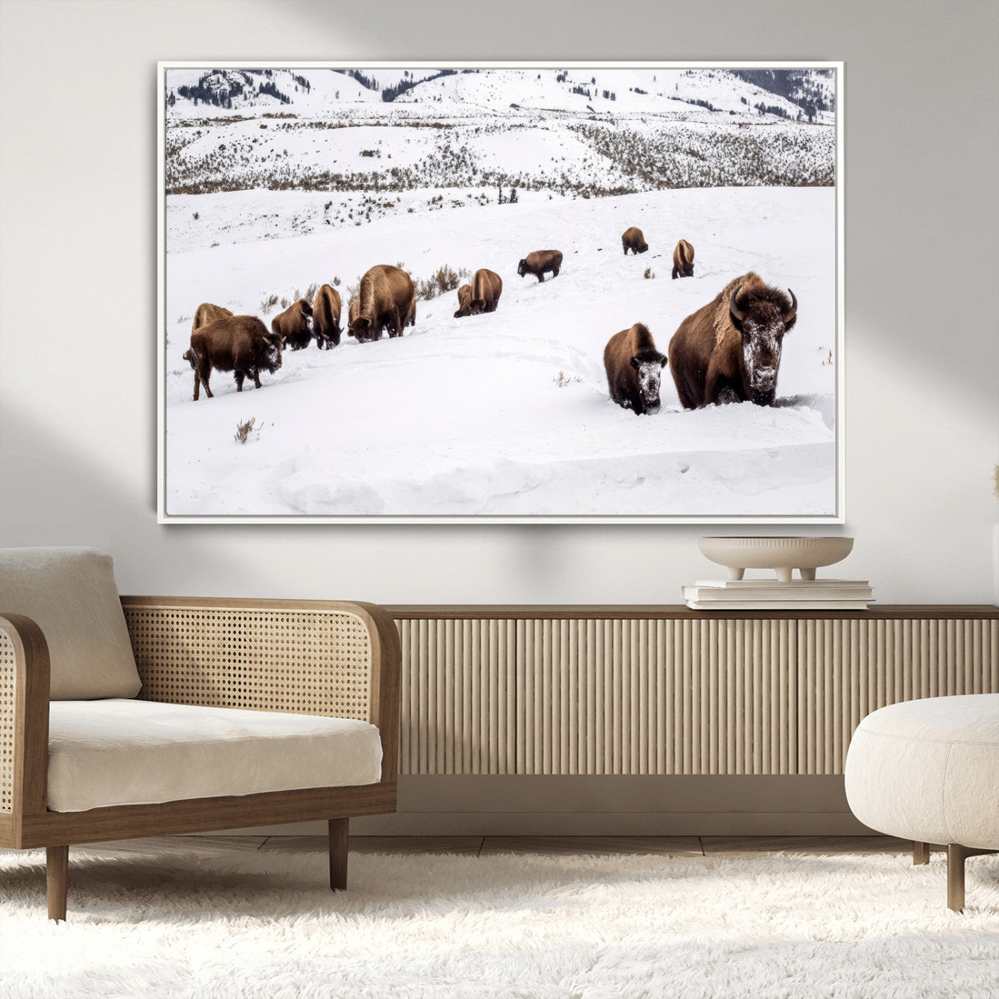 A herd of bison walking through deep snow in a mountain valley, perfect for rustic, cabin or western-themed wall decor.