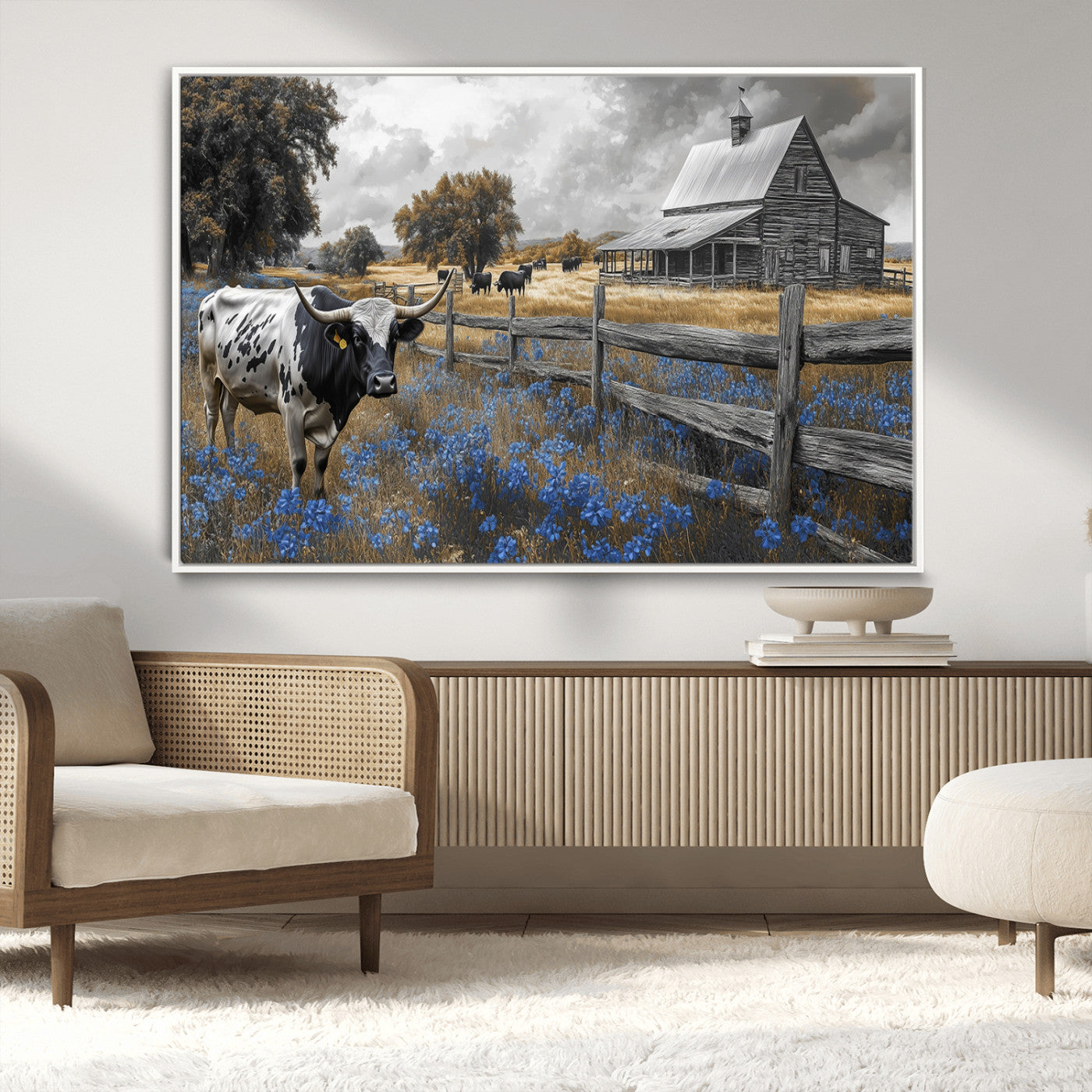 A Texas longhorn stands in front of a rustic barn and wooden fence, with bluebonnets and grazing cattle under dramatic skies.