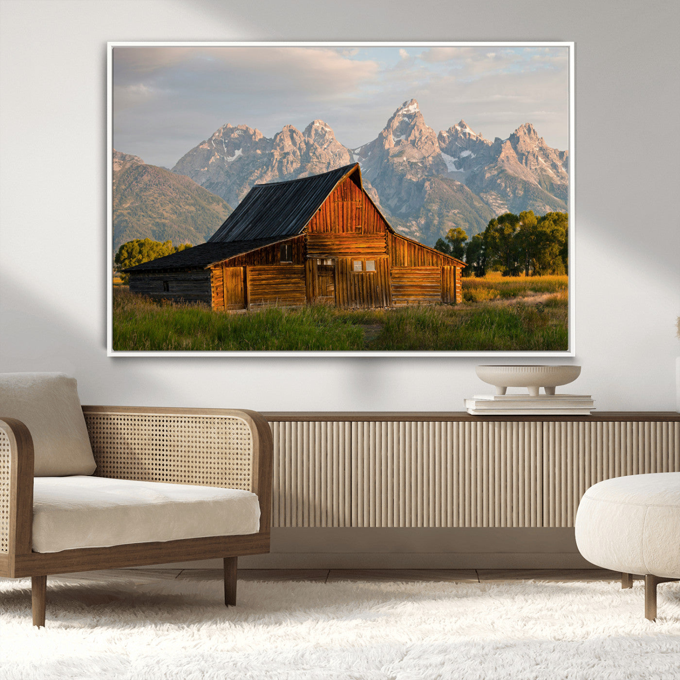 Rustic wooden barn set against towering mountain peaks under warm golden light, creating a peaceful Western countryside scene.