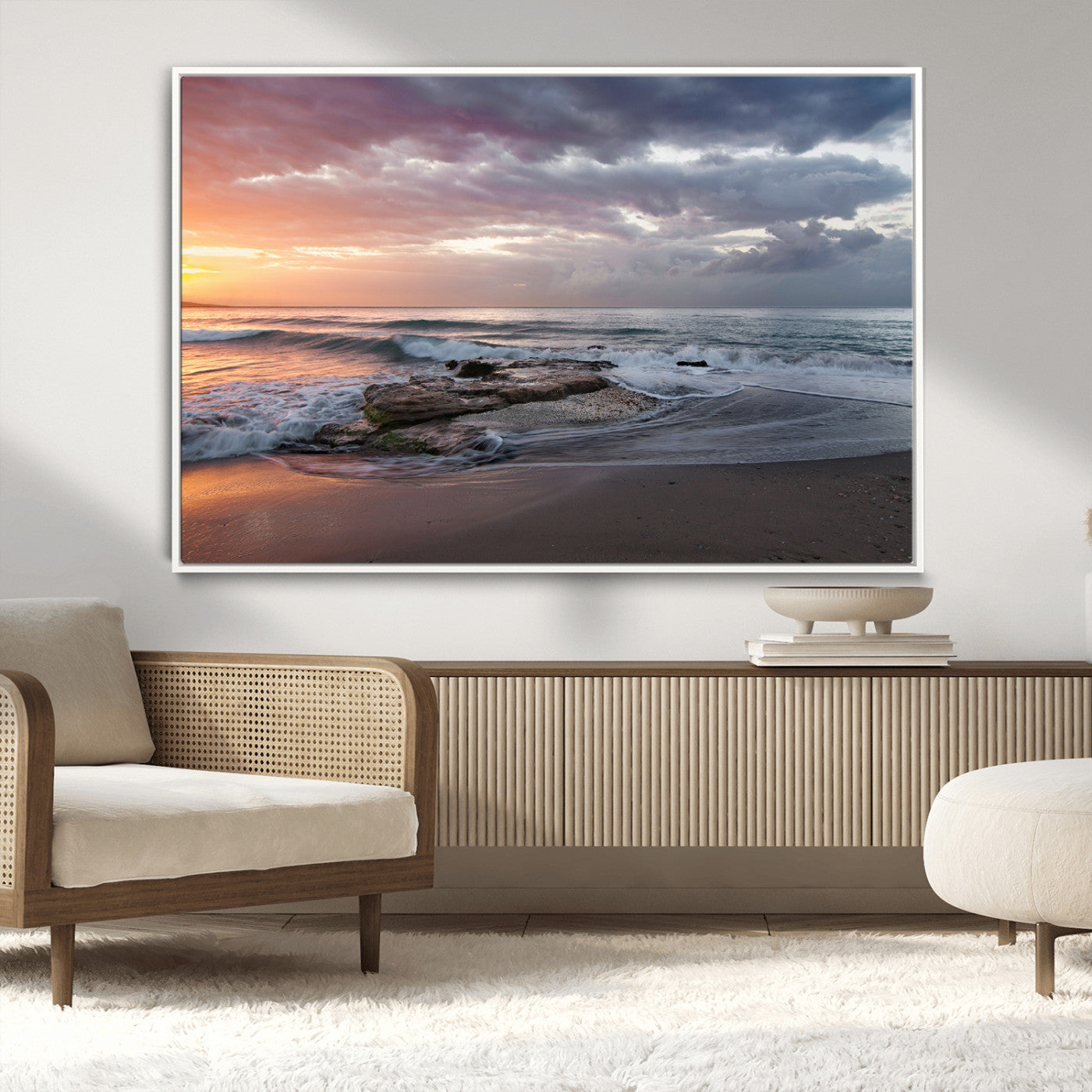 Dramatic sunset over a rocky shoreline with ocean waves gently reaching the sandy beach, creating a serene and coastal atmosphere.