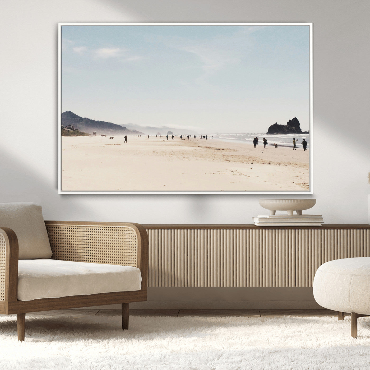 A serene beach with soft sand, misty mountains, and scattered people walking along the shoreline, creating a peaceful coastal landscape.