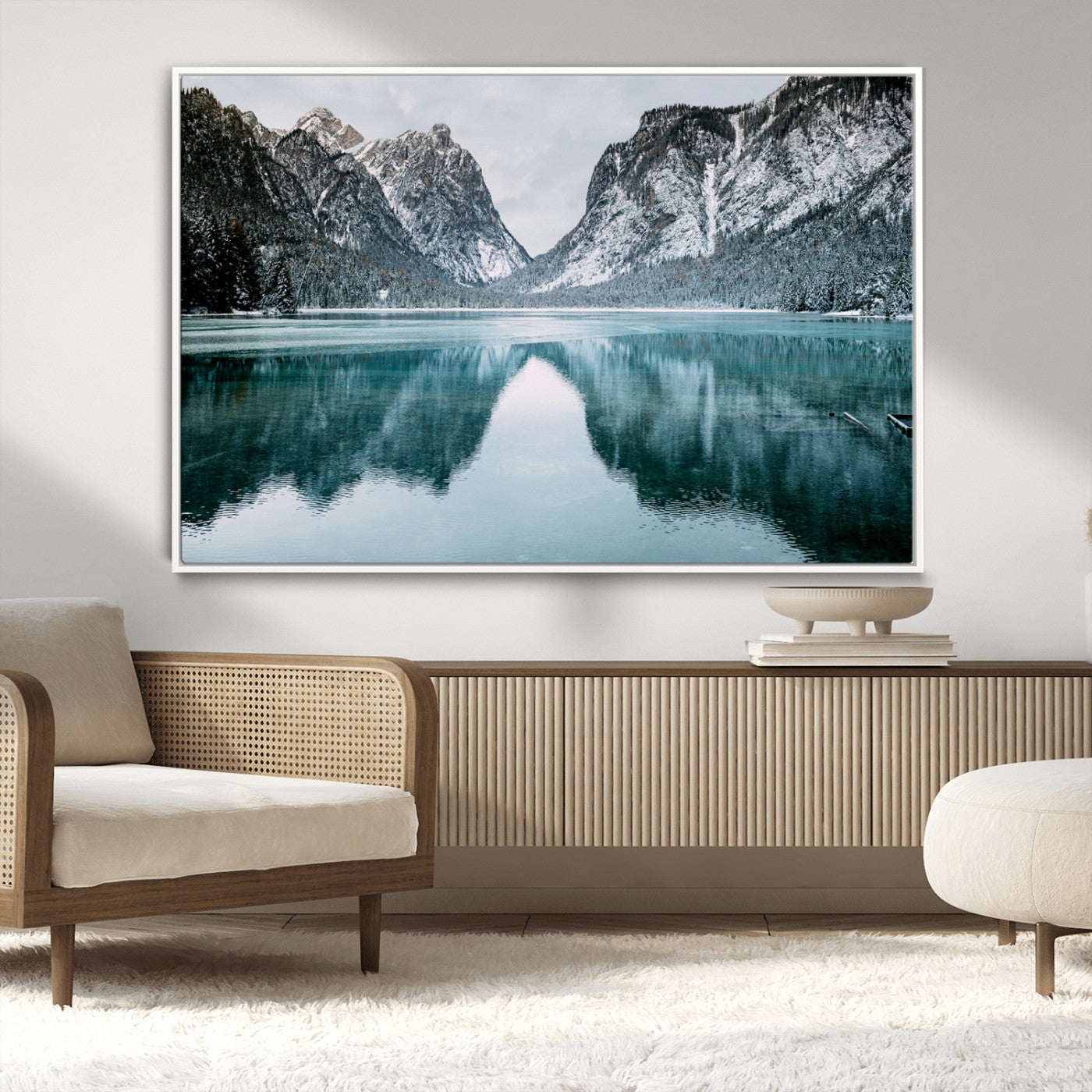 Crystal-clear alpine lake reflecting snow-covered mountains, surrounded by evergreen trees, creating a serene and tranquil winter landscape.