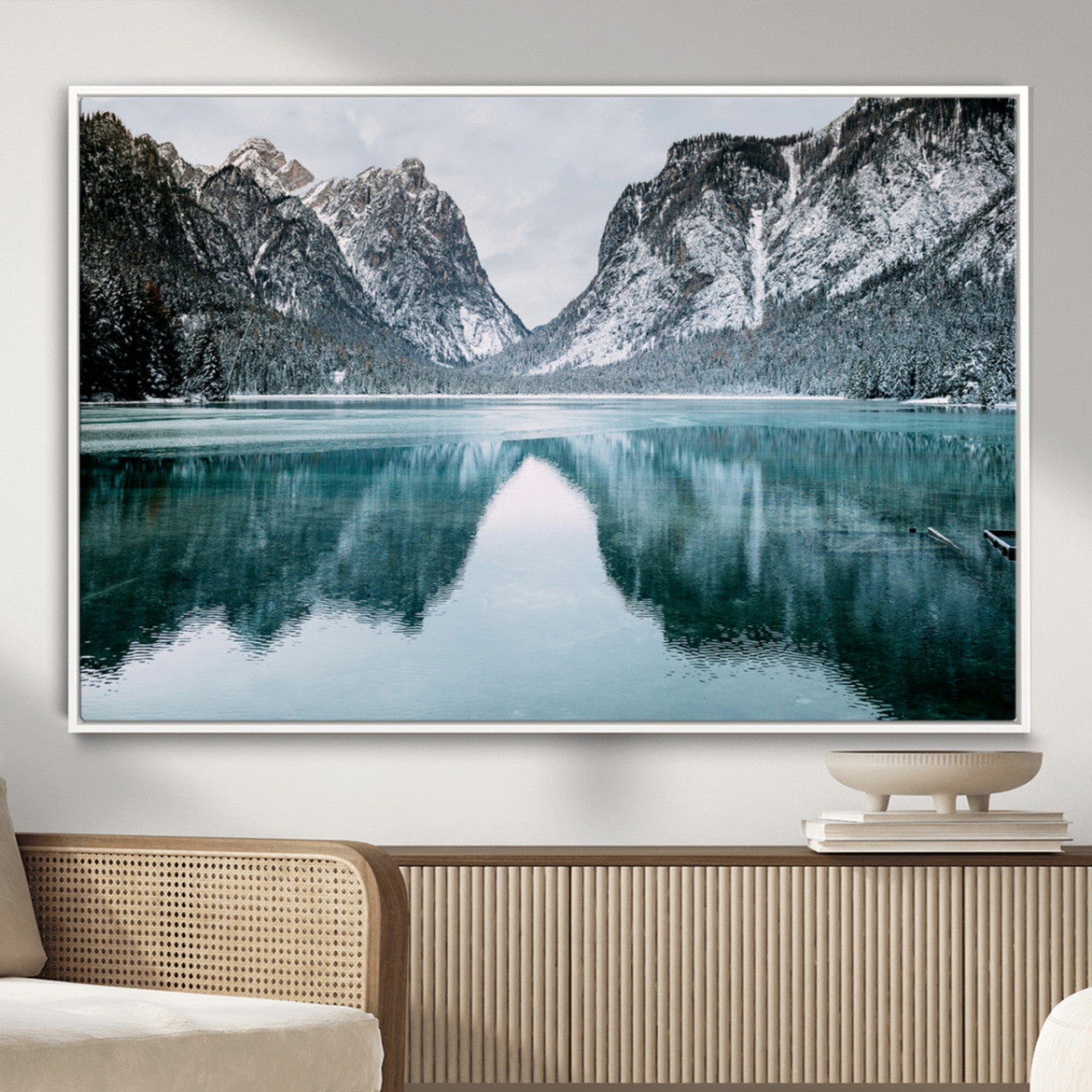 Crystal-clear alpine lake reflecting snow-covered mountains, surrounded by evergreen trees, creating a serene and tranquil winter landscape.